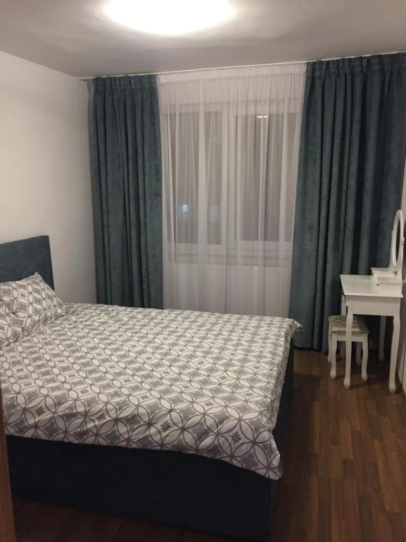 1 dormitorio con cama, escritorio y ventana en Apartament 3 camere Royal Brasov en Brasov