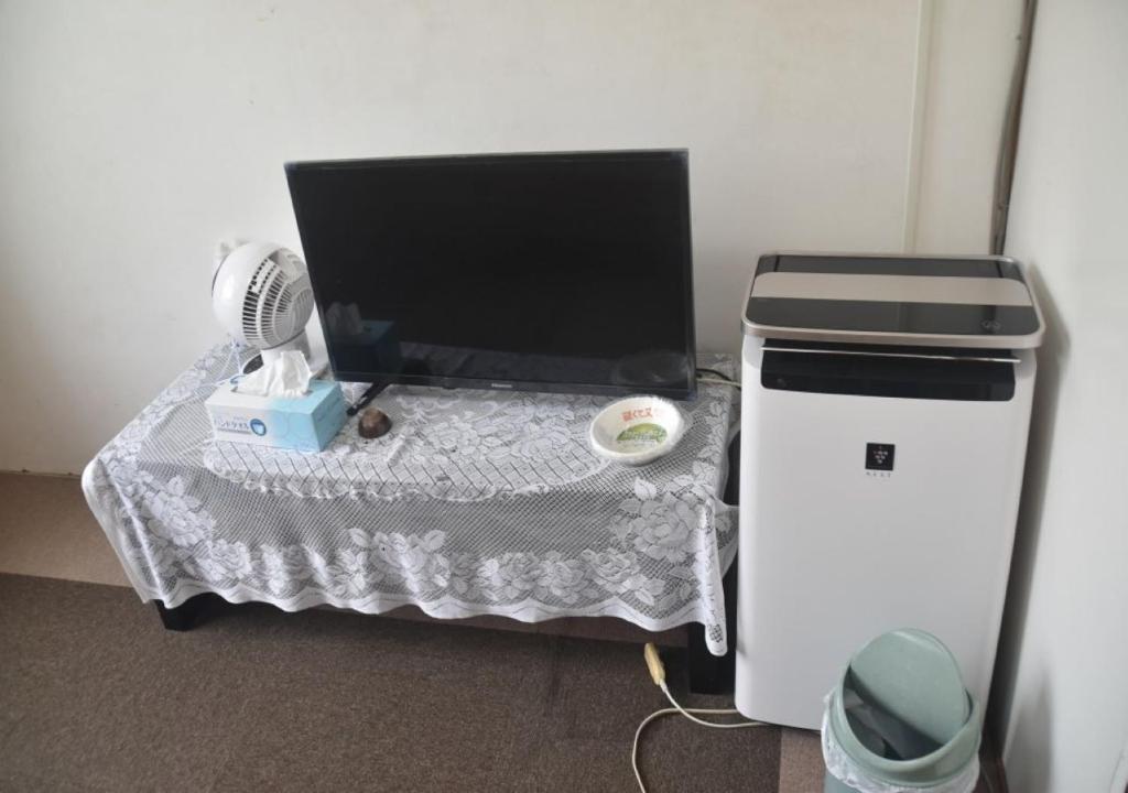 einen Schreibtisch mit einem Computer auf einem Tisch und einem Ventilator in der Unterkunft Guest House Minatoya Tokunoshima - Vacation STAY 01040v in Tokunoshima