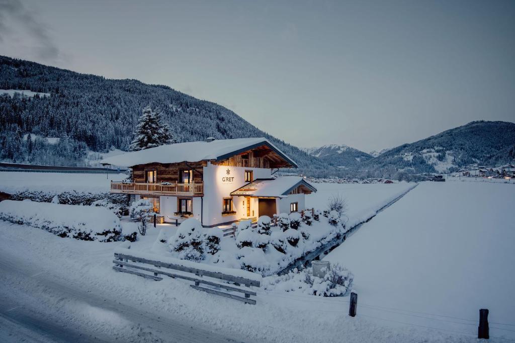 een huis bedekt met sneeuw naast een meer bij Alpin Apartement G'ret in Flachau