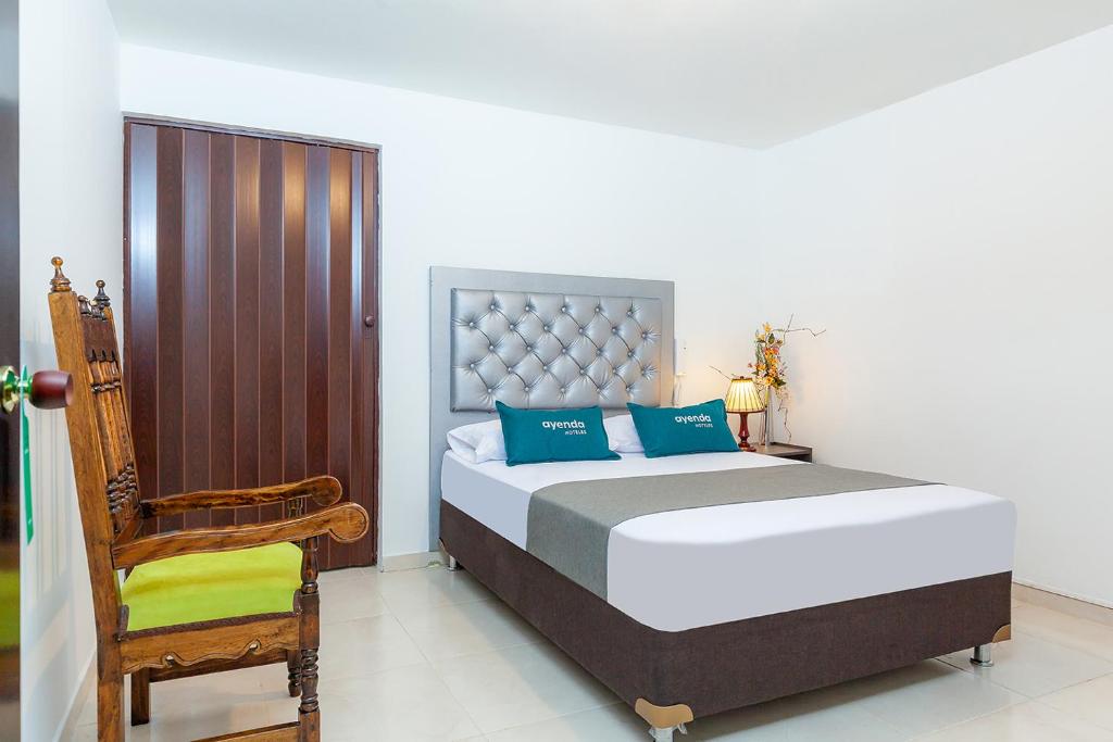 een slaapkamer met een groot bed en een stoel bij Ayenda Colina Real in Pasto
