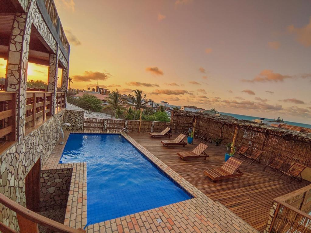 a swimming pool with a deck and chairs and the ocean at Pousada Bella Mar in Prea