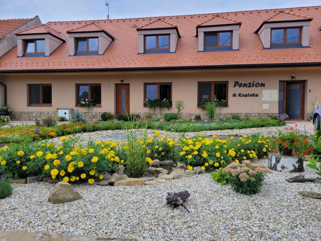 einen Garten vor einem Gebäude mit gelben Blumen in der Unterkunft Penzion U Kostela in Kuželov