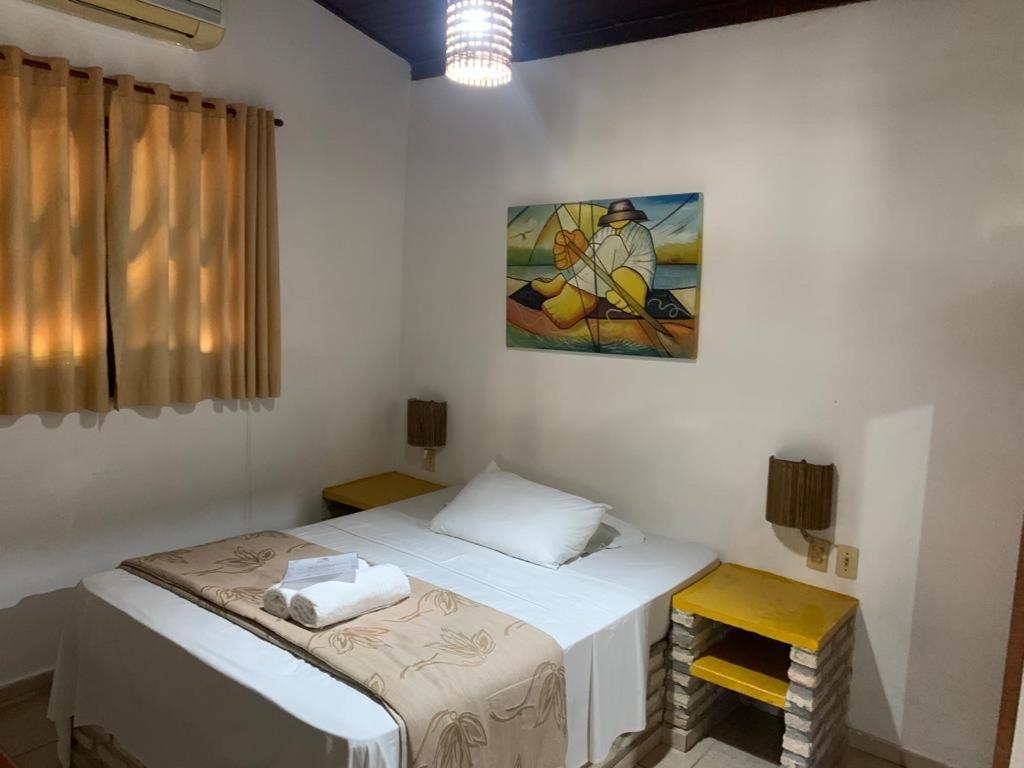 Habitación con 2 camas y una pintura en la pared. en Porto do Sol - Chalé 13, en Pipa