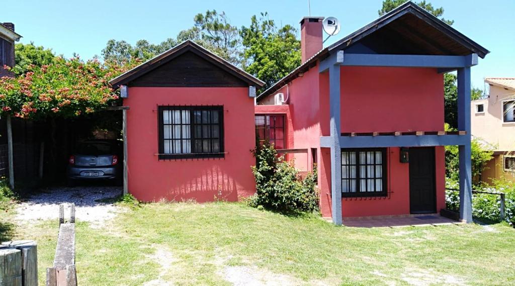 une maison rouge avec une voiture garée à côté dans l'établissement Casa Roja, à Playa Verde