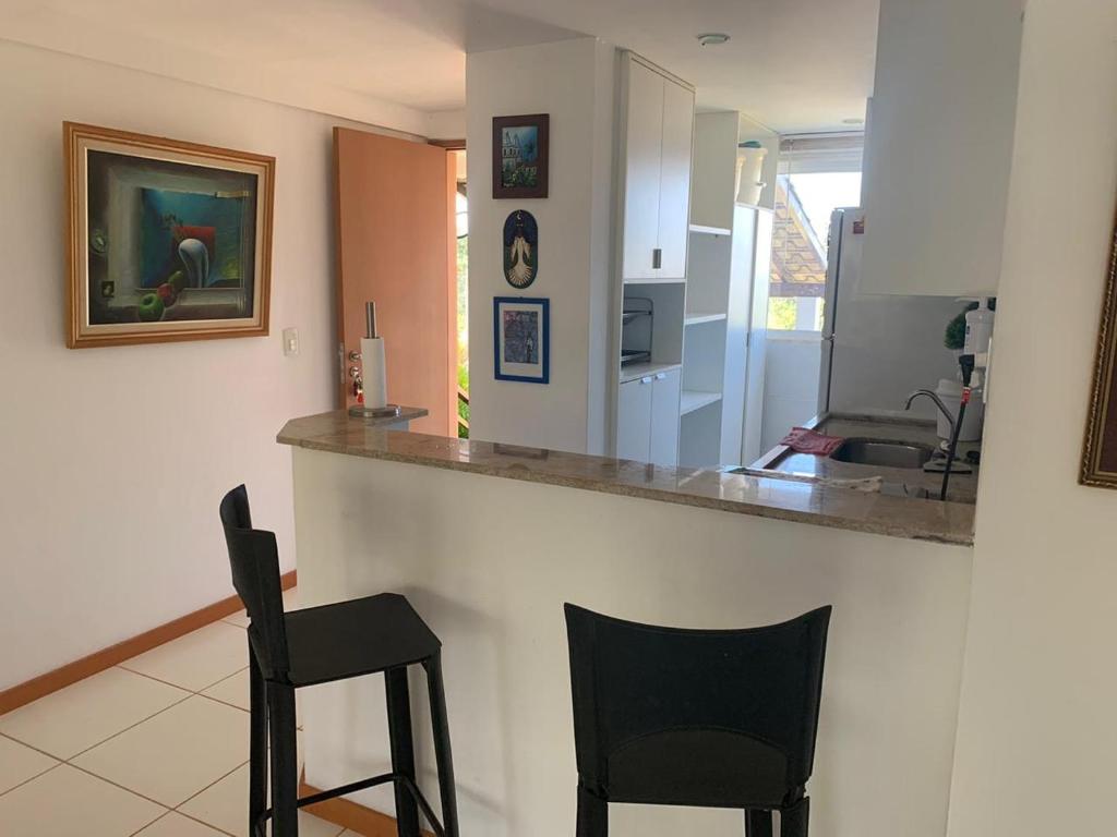 a kitchen with two black chairs and a counter at Condomínio Lírios Paraíso de Paz e Beleza in Mata de Sao Joao