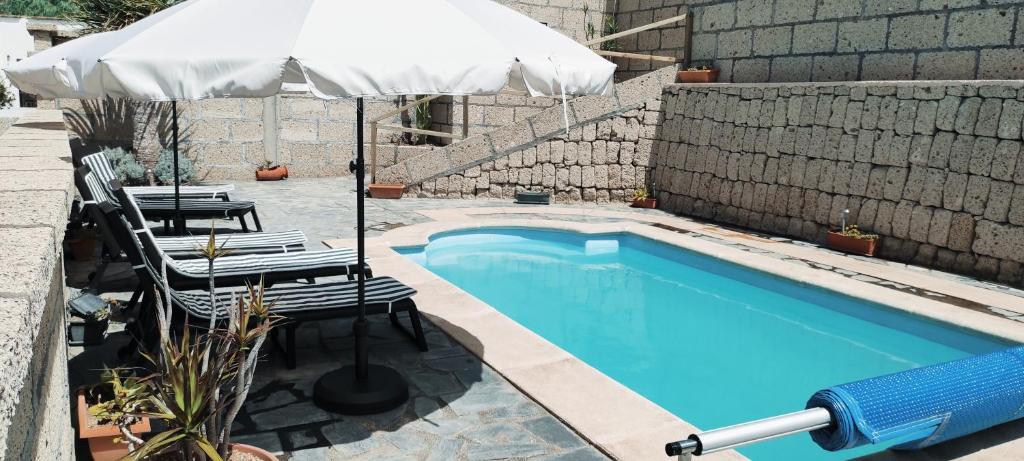a swimming pool with an umbrella and chairs and a table and an umbrella at Villa Cubas in Güimar