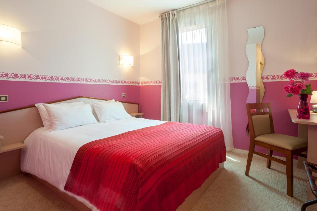 a bedroom with a bed and a chair and a window at BRIT HOTEL Le Lion d'Or CHINON in Chinon