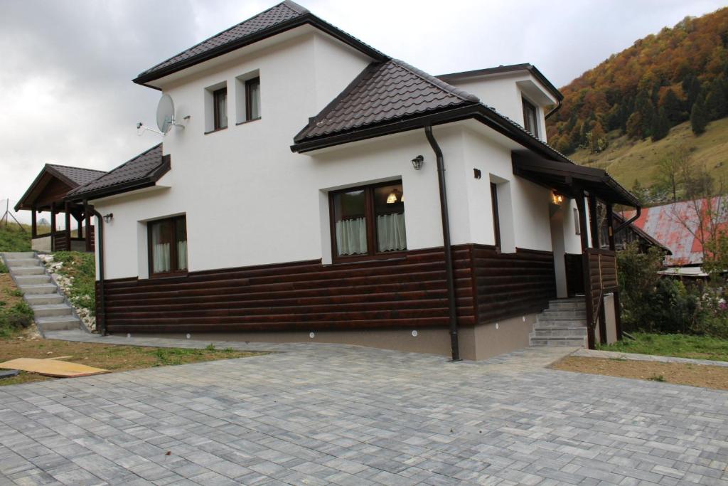 une maison blanche avec un toit noir et une allée. dans l'établissement Rekreačný dom za Potokom, à Stredná Revúca