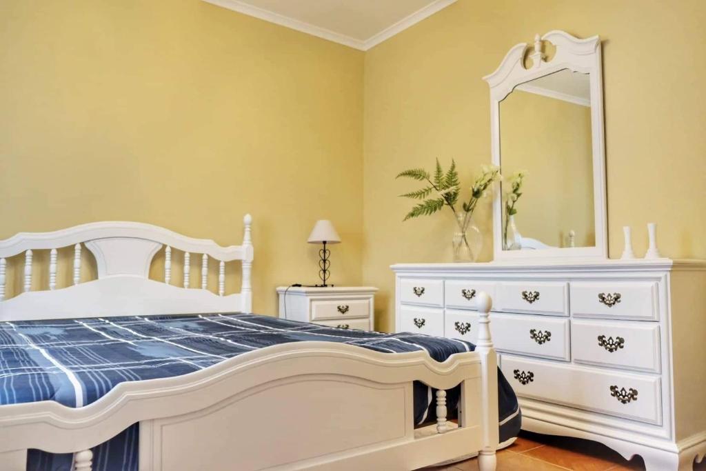 a white bedroom with a white dresser and a mirror at Ribeirinha House in Porto Formoso