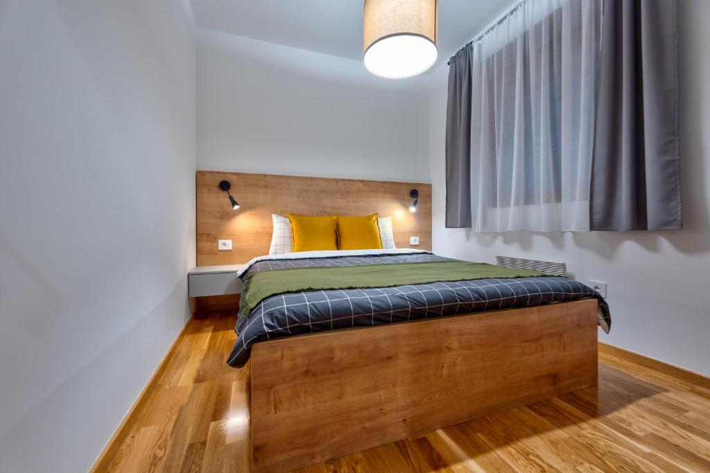 a bedroom with a bed with a yellow pillow at WALD Apartmani&SPA in Zlatibor