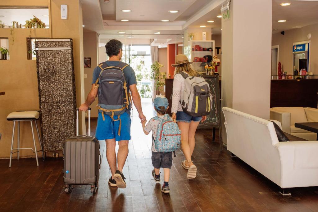 a family walking through a store with their luggage at Tangoinn Club Hotel in San Carlos de Bariloche