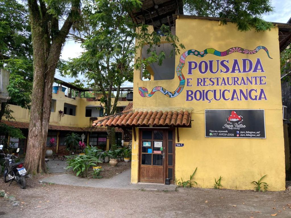 a yellow building with a sign for a restaurant at Pousada Boiçucanga a 30m da praia in Boicucanga