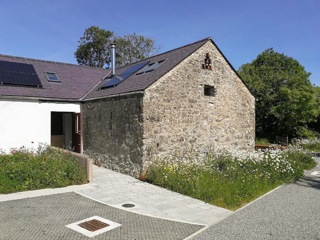 an old stone building with a black roof at Beudy Bodeilio in Llangefni