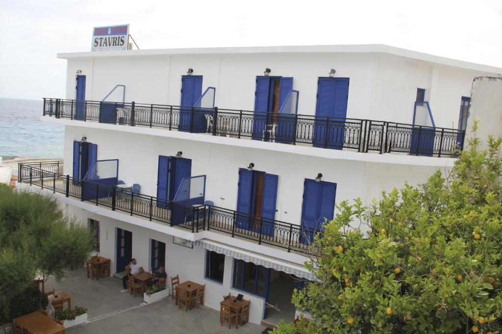 un edificio blanco con puertas azules, mesas y sillas en Hotel Stavris, en Chóra Sfakíon