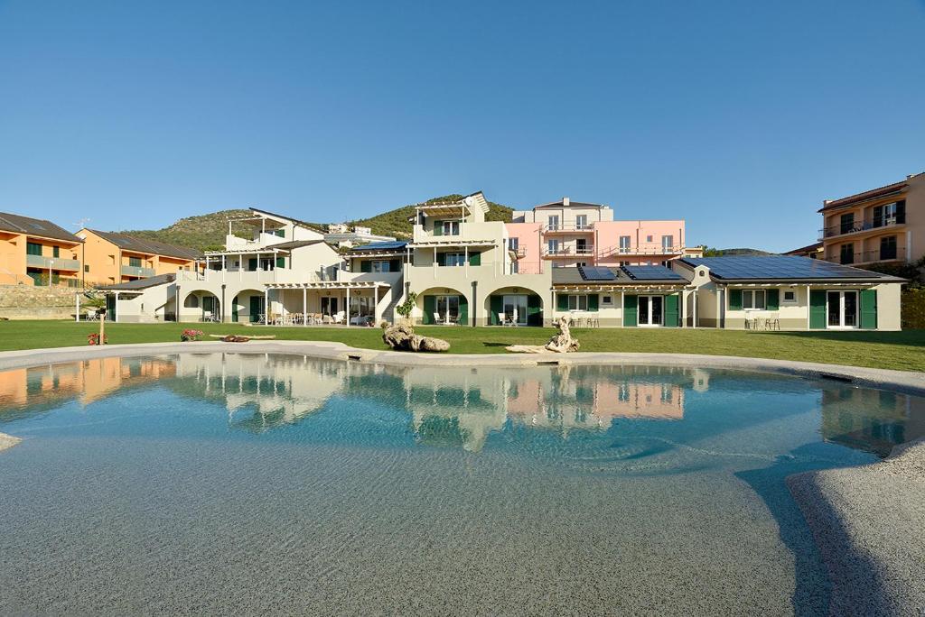 una grande piscina d'acqua di fronte ad alcune case di Barbaciiu Vacanze Green a Pietra Ligure