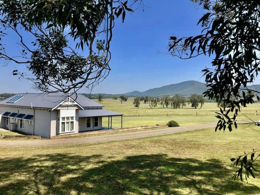 a white house in the middle of a field at Kinsale Cottage in Pokolbin