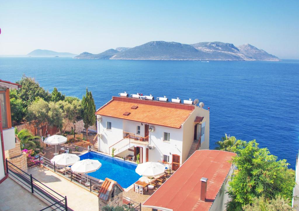 a house with a swimming pool next to the ocean at Sunset Villa Hotel in Kaş