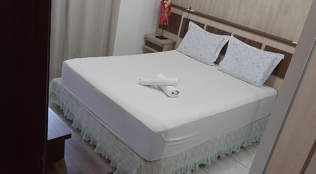 1 cama grande con sábanas y almohadas blancas en Apartamento Inteiro jardim Iririú, en Joinville