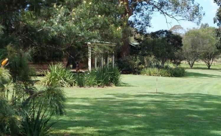拉夫代爾的住宿－Cabins at Lovedale Wedding Chapel，郁郁葱葱的绿色庭院,种植了树木,设有高尔夫球场