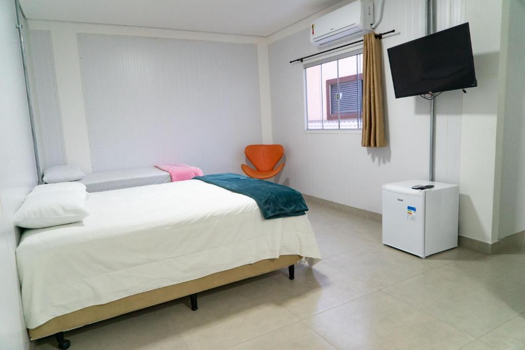 a bedroom with a bed and a tv and a chair at Flat Central in Bonito