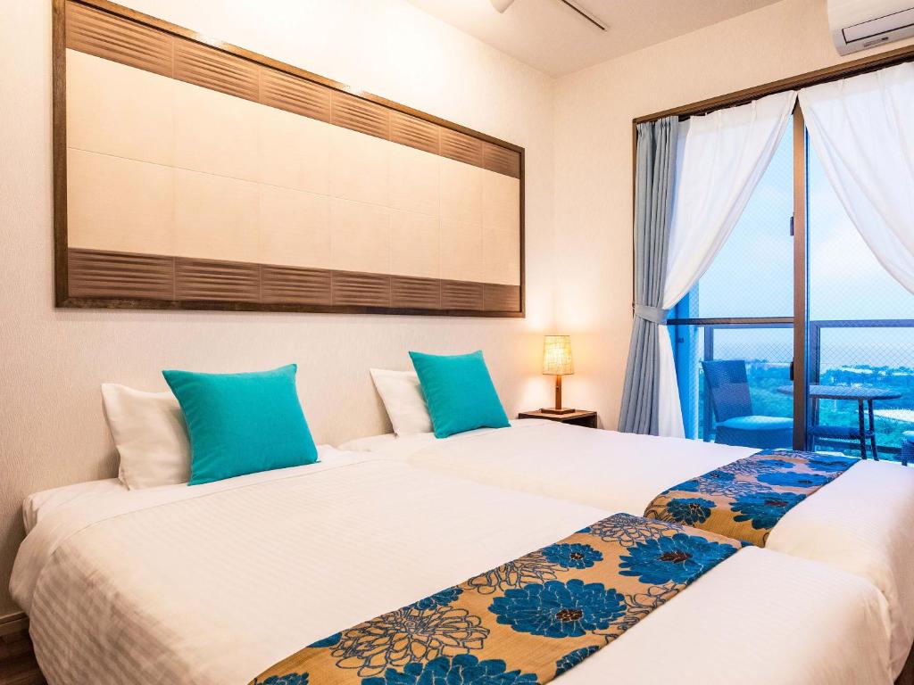 two beds in a room with a window at Yukurina Resort Okinawa in Motobu