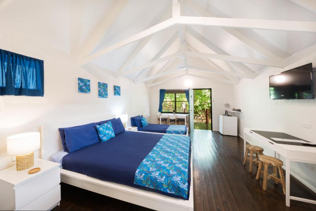 a white bedroom with a blue bed and a desk at Airlie Beach Magnums - Adults Only in Airlie Beach