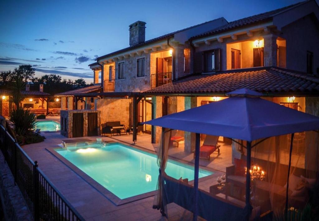 uma casa com piscina e guarda-sol em Villa Berna - pool house em Malinska