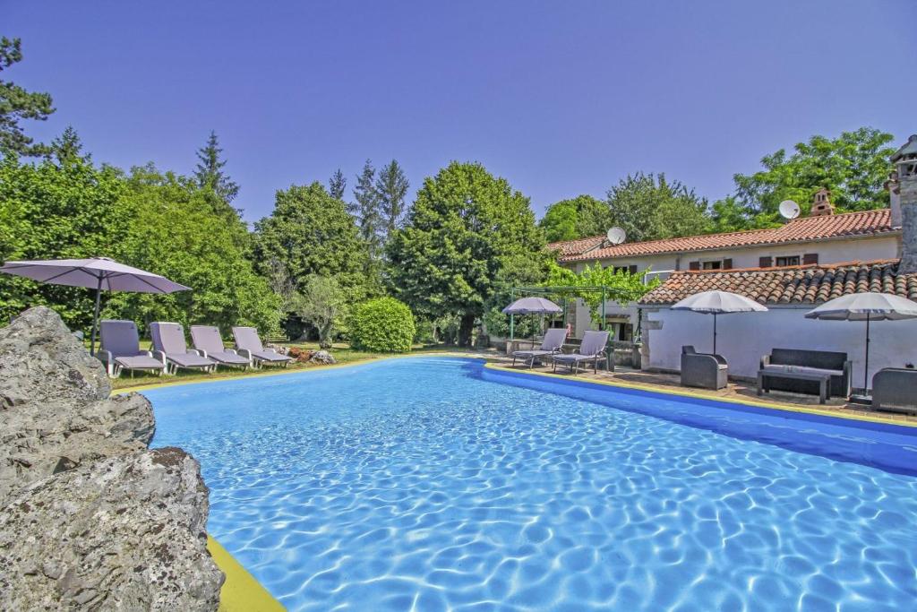 einen Pool mit Stühlen und Sonnenschirmen neben einem Haus in der Unterkunft Filip in Kraj Drage (Haus für 4-5 Personen) in Nedeščina