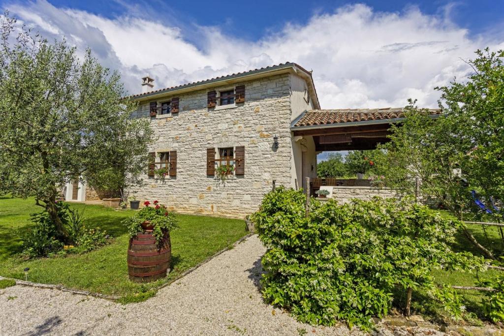 ein großes Steinhaus mit einem Garten mit Büschen in der Unterkunft Galant in Prkačini (Haus für 4-5 Personen) in Žminj