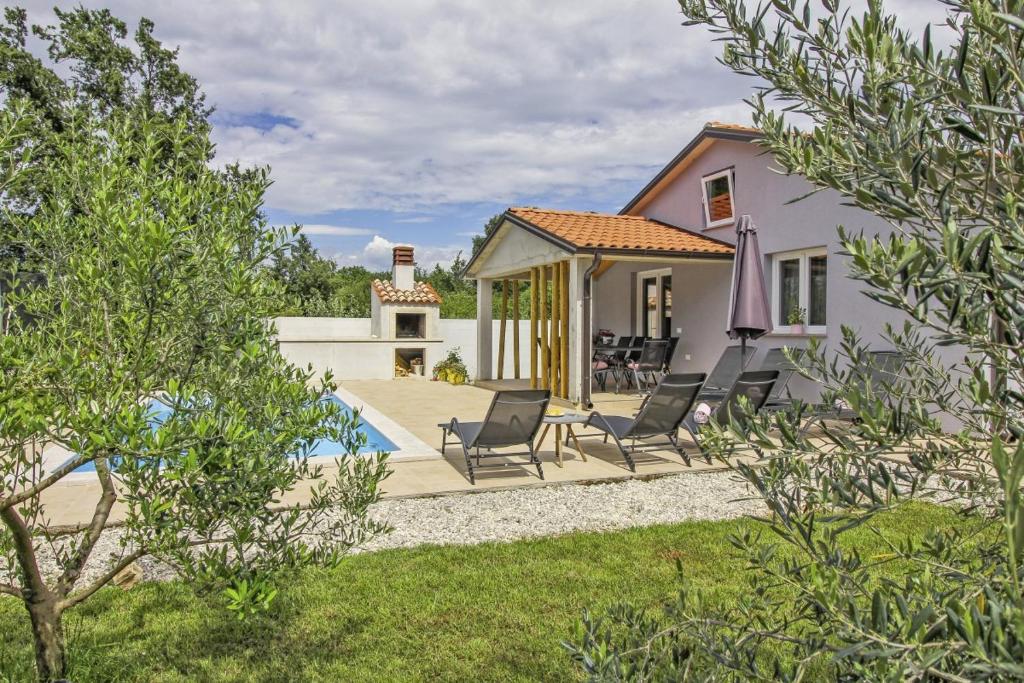 a house with chairs and an umbrella in a yard at Natascha in Pamići (Haus für 6-8 Personen) in Žminj