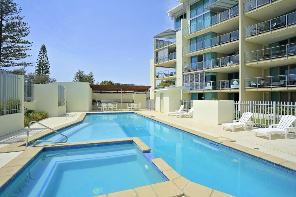 una piscina frente a un edificio de apartamentos en Ground Floor Luxury Oceanfront Apartment, en Bargara