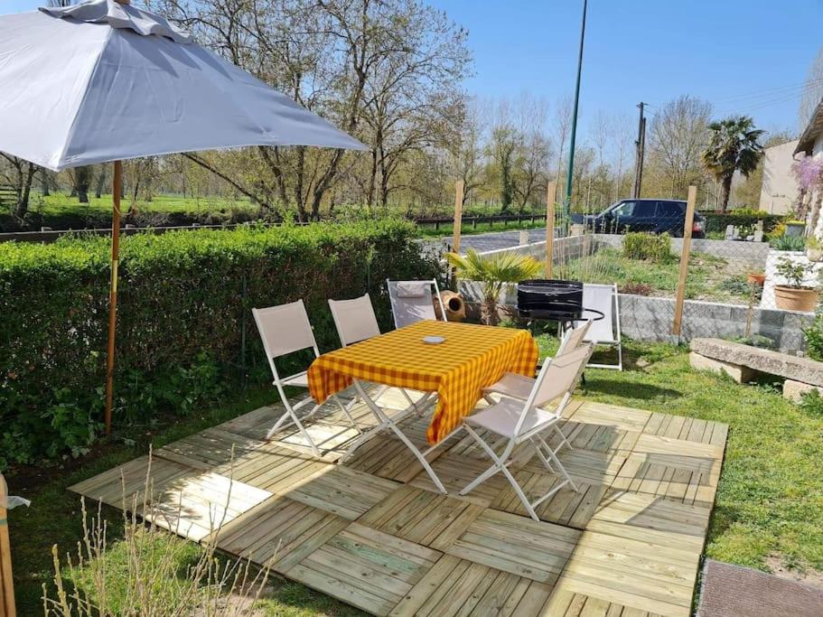 een tafel en stoelen met een parasol in de tuin bij Le logis du héron in Coulon