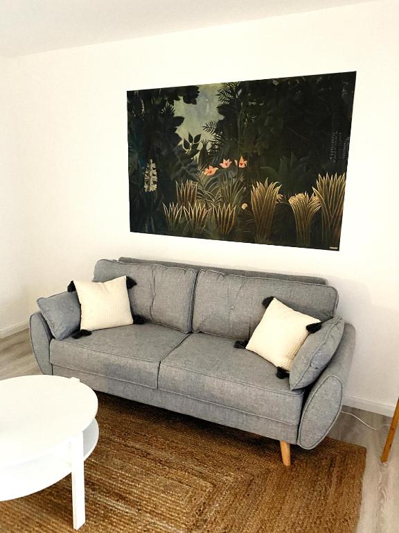 a living room with a couch and a painting on the wall at Sélina by Les Suites d&#39;Alfred in Saint-Denis