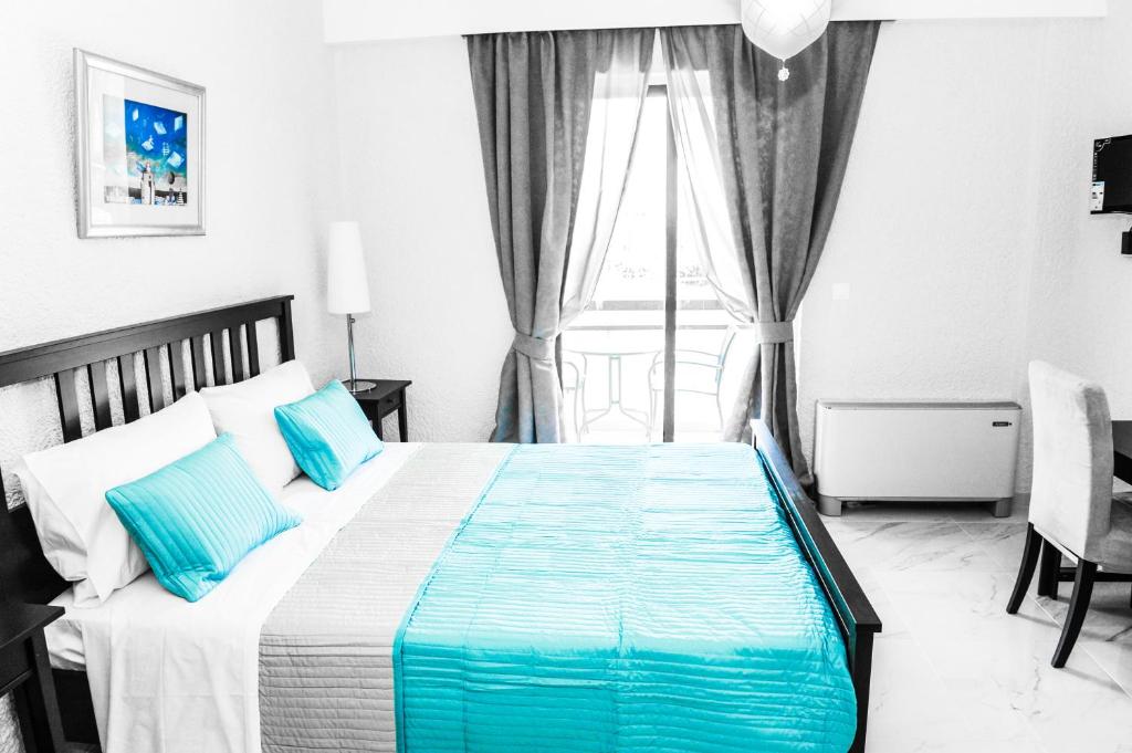 una camera da letto con un letto con cuscini blu e una finestra di Valentino Hotel a Kremasti