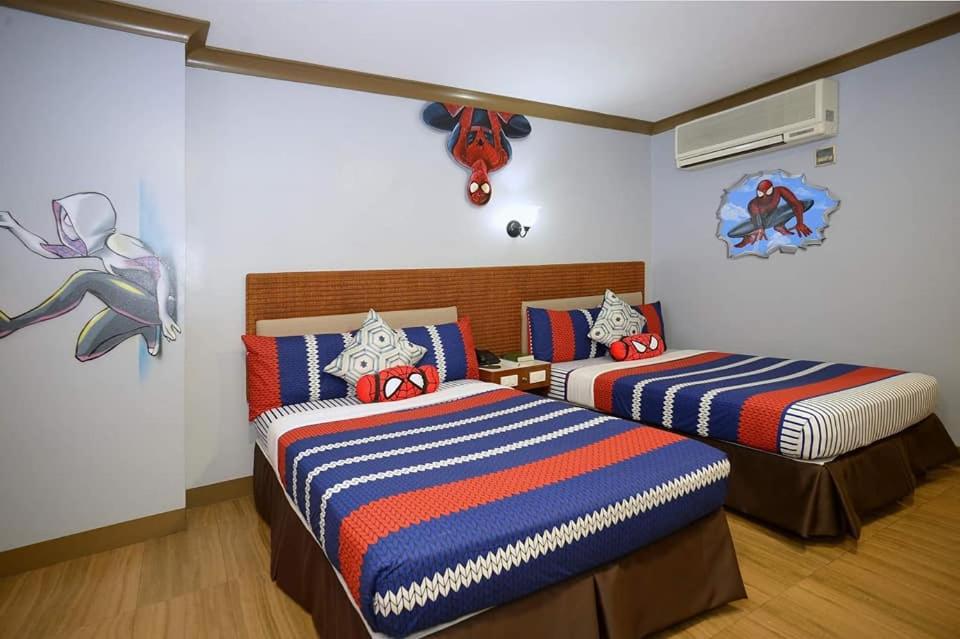 ein Schlafzimmer mit 2 Betten und einem Wandgemälde in der Unterkunft The Golden Pine Hotel in Baguio City