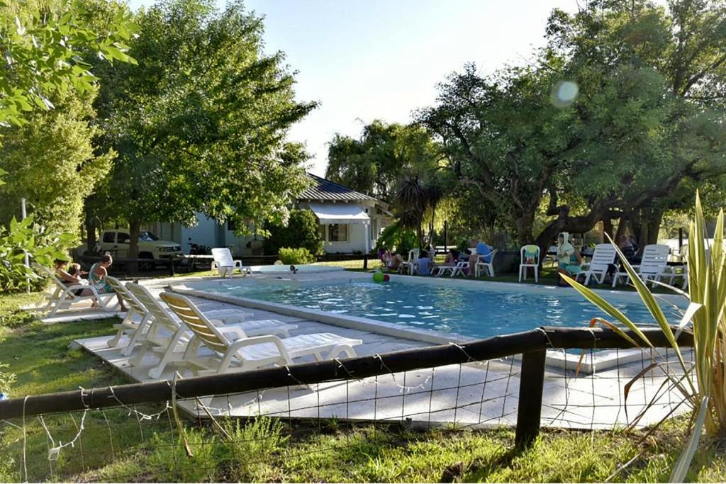 una piscina con sillas y gente sentada a su alrededor en Puerto Sosiego en Gualeguaychú