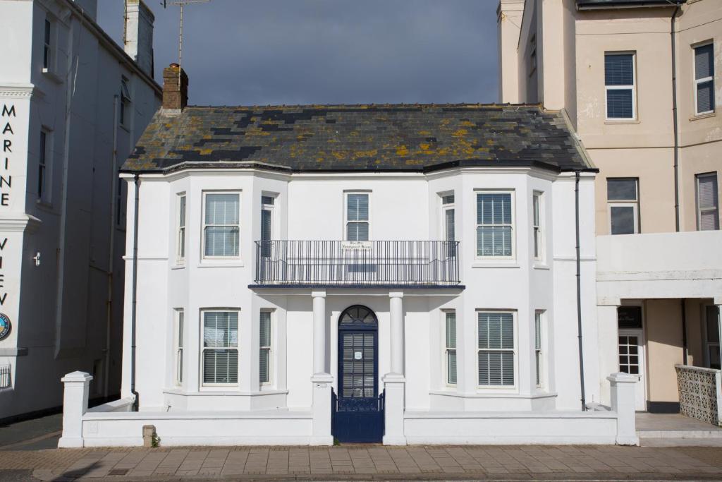 a white house with a balcony on a street at The Old Coastguard House in Worthing