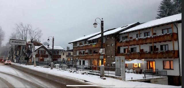 a snow covered street in a town with buildings at Olympic regina hotel in Pinzolo