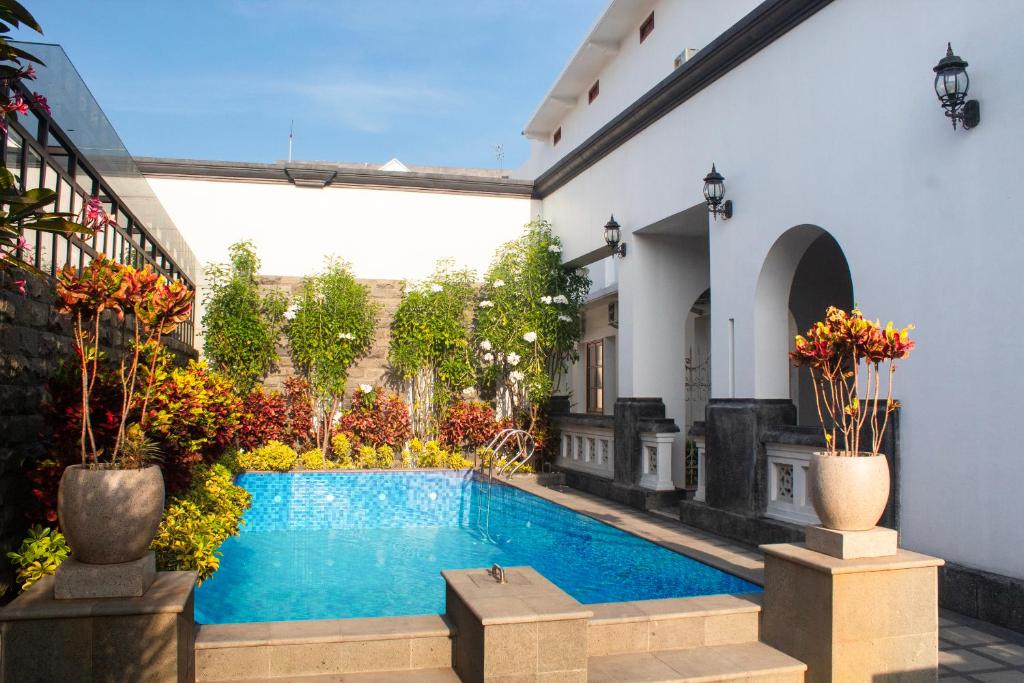 岩望的住宿－Daroessalam Syariah Heritage Hotel，植物繁茂的建筑中间的游泳池