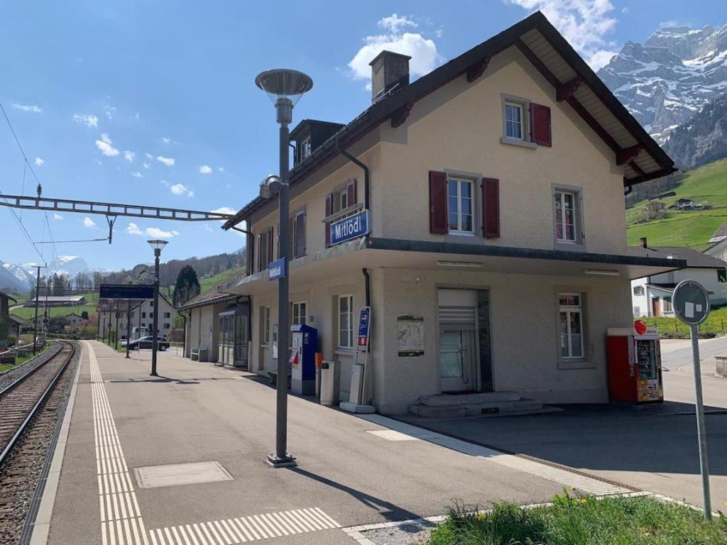 a building next to a train station with mountains at Revier schlicht und bahnsinnig in Mitlödi