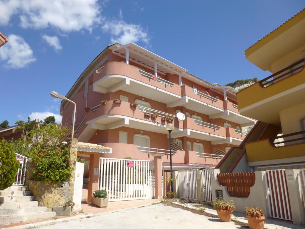 un edificio rosa con una valla y algunas plantas en Appartamenti Scala Dei Turchi Villa Saporito, en Realmonte