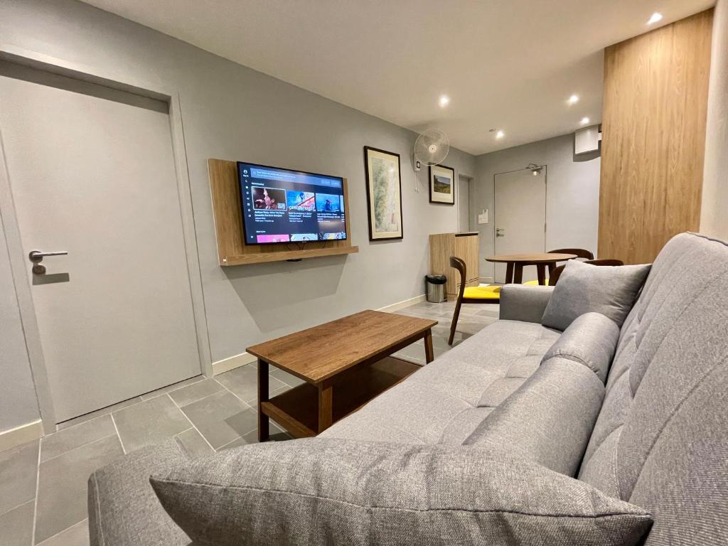 LV Modern Suite Langkawi by Zervin في كواه: غرفة معيشة مع أريكة وتلفزيون بشاشة مسطحة