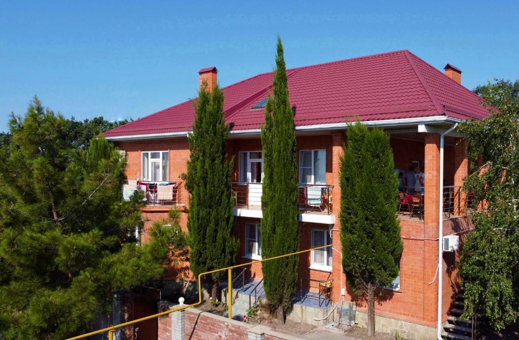 una casa de ladrillo rojo con árboles delante de ella en Мини-отель La Villa, en Gelendzhik