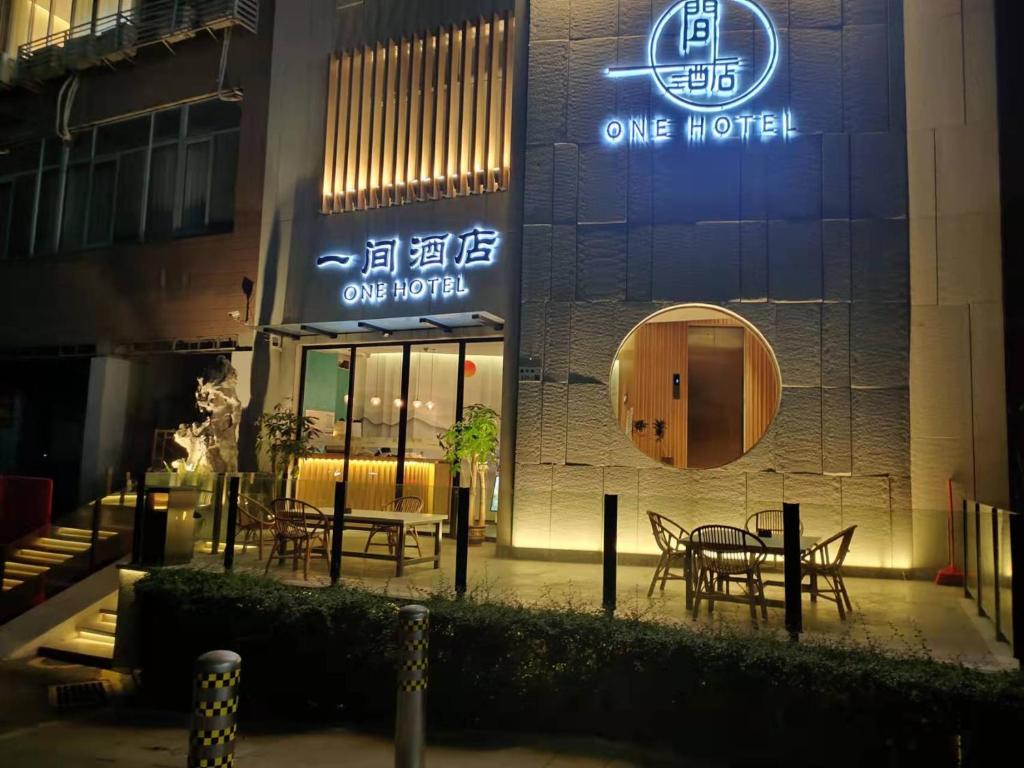een hotel met tafels en stoelen buiten 's nachts bij One House in Shenzhen