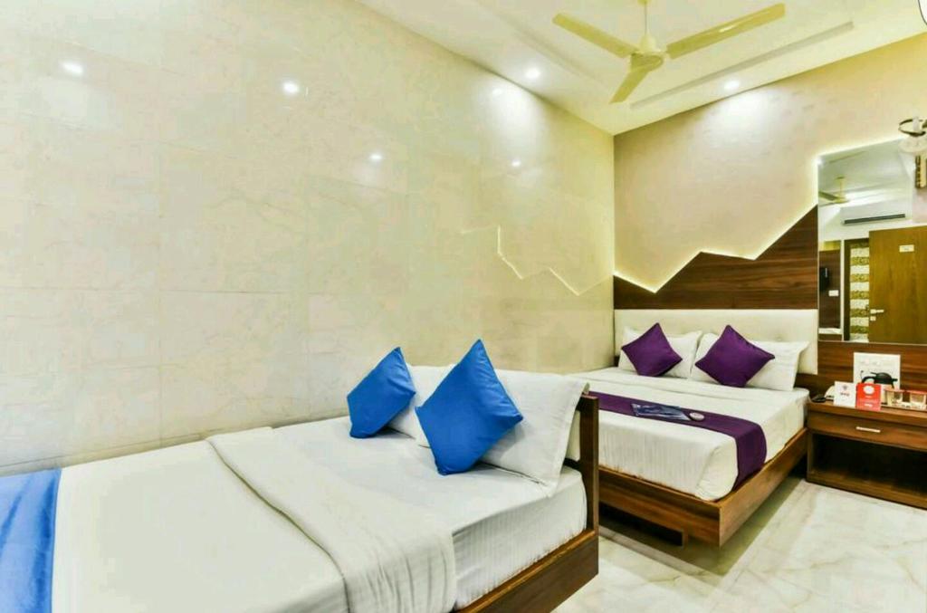 Hotel Palace Residency near Lokmanya Tilak Terminus في مومباي: سريرين في غرفة مع وسائد زرقاء وأرجوانية