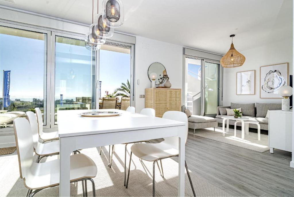 uma sala de jantar branca com uma mesa e cadeiras brancas em LM12A- Brand new apartment in a quiet location em Estepona