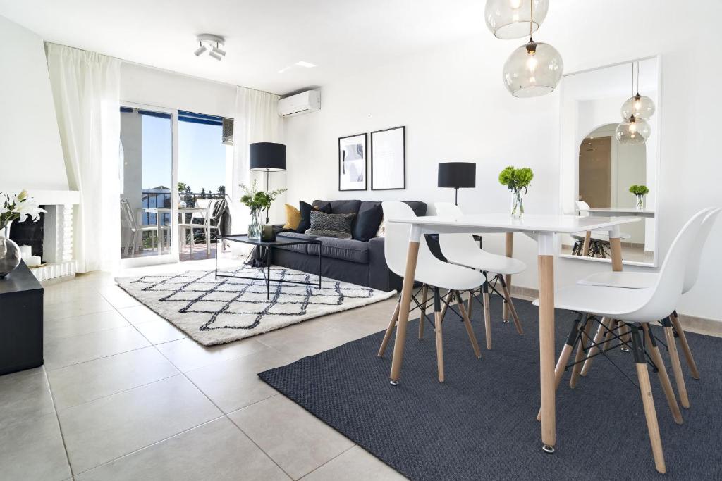 ein Esszimmer und ein Wohnzimmer mit einem weißen Tisch und Stühlen in der Unterkunft RDM - Stylish Holiday Apartment with Ocean Views in Mijas