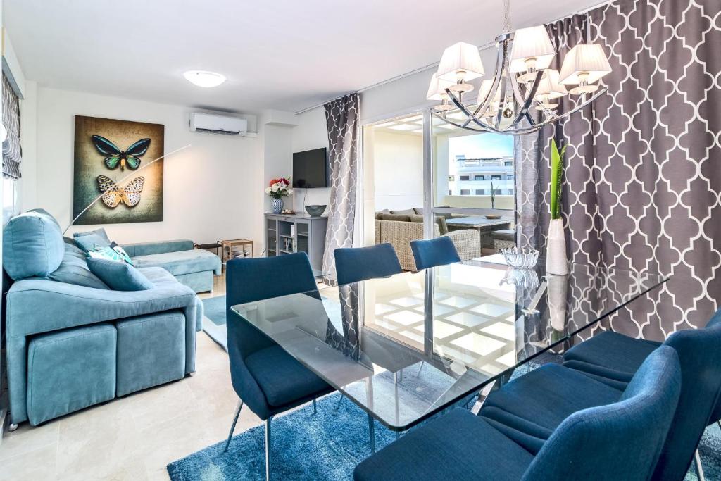 ein Wohnzimmer mit einem Glastisch und blauen Stühlen in der Unterkunft PDM- Lovely apartment with stunning views Estepona in Estepona