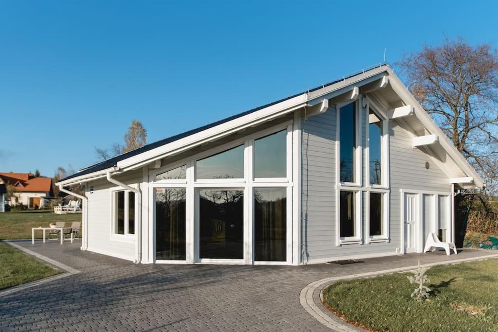 a white house with large glass doors on it at Babiogórska Perełka w skandynawskim stylu z sauną i kominkiem in Jordanów