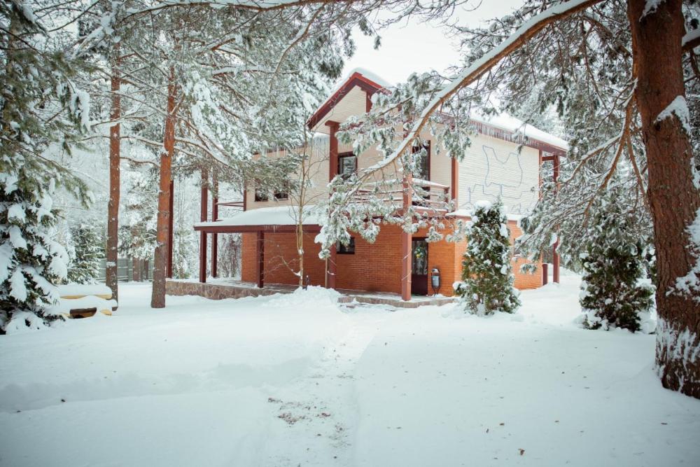 una casa con nieve en el suelo delante de ella en Дивный Мир Хижина, en Baranovo
